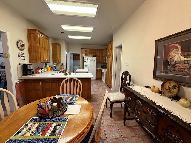 kitchen featuring kitchen peninsula, white appliances, and light tile patterned floors