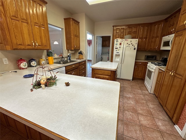 kitchen featuring white appliances, a kitchen island, sink, kitchen peninsula, and washer / clothes dryer