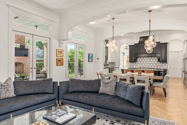 living room with a chandelier, light parquet flooring, crown molding, and french doors