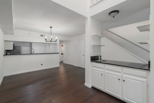 kitchen featuring pendant lighting, dark wood-type flooring, an inviting chandelier, white cabinets, and stainless steel fridge