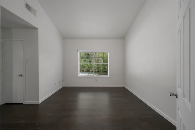 spare room with lofted ceiling and dark wood-type flooring