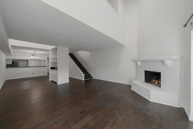 unfurnished living room featuring a fireplace, dark wood-type flooring, and a chandelier