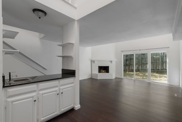 unfurnished living room featuring sink and dark hardwood / wood-style floors