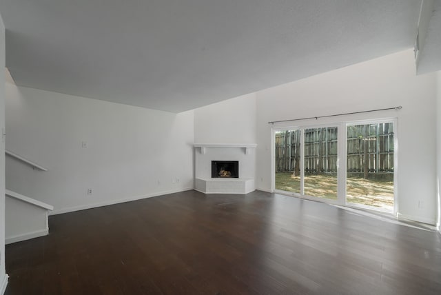 unfurnished living room featuring a fireplace and dark wood-type flooring