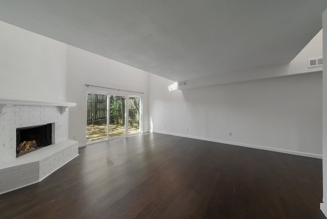 unfurnished living room with dark wood-type flooring and a brick fireplace