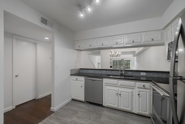 kitchen with hardwood / wood-style floors, white cabinets, sink, appliances with stainless steel finishes, and a notable chandelier