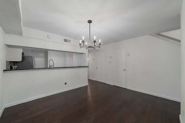 kitchen featuring dark wood-type flooring, white cabinets, sink, decorative light fixtures, and stainless steel refrigerator