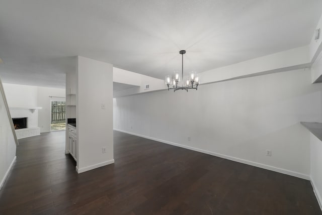 unfurnished dining area featuring a fireplace, dark hardwood / wood-style flooring, and an inviting chandelier