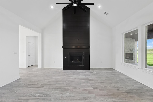 unfurnished living room featuring ceiling fan, light hardwood / wood-style floors, high vaulted ceiling, and a large fireplace