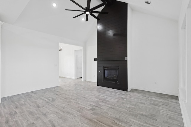 unfurnished living room with a large fireplace, high vaulted ceiling, light wood-type flooring, and ceiling fan