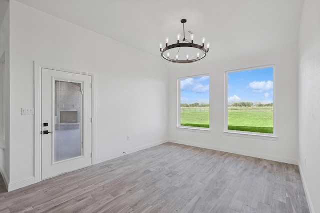 spare room featuring a notable chandelier and light hardwood / wood-style floors