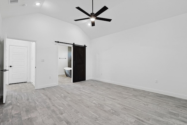 unfurnished bedroom featuring a barn door, ceiling fan, light hardwood / wood-style flooring, high vaulted ceiling, and connected bathroom