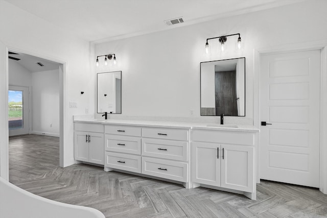 bathroom with vanity, parquet flooring, vaulted ceiling, and a washtub