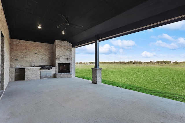 view of patio with ceiling fan, a rural view, and an outdoor kitchen