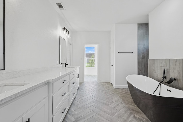 bathroom with vanity, a bathtub, and parquet flooring