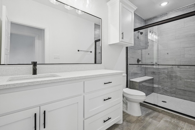 bathroom with walk in shower, vanity, hardwood / wood-style floors, and toilet