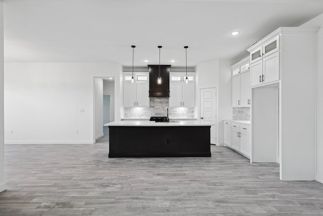 kitchen featuring decorative light fixtures, custom range hood, white cabinetry, and a kitchen island