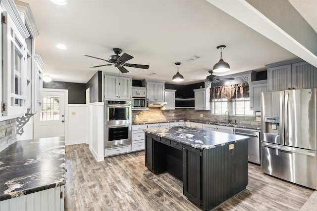 kitchen with a wealth of natural light, hardwood / wood-style flooring, stainless steel appliances, and a center island