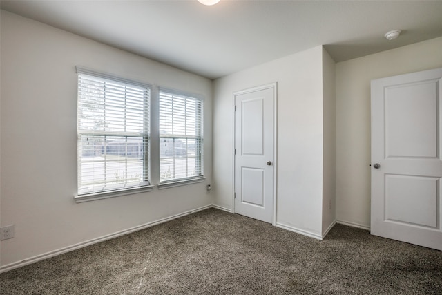 unfurnished bedroom featuring dark colored carpet and a closet