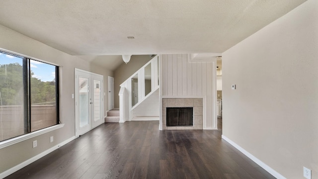 unfurnished living room featuring a textured ceiling, dark hardwood / wood-style floors, and a tiled fireplace