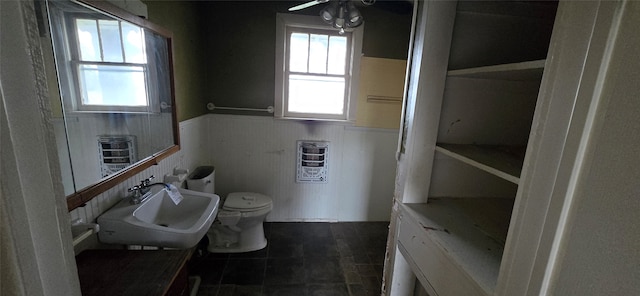 bathroom with ceiling fan, a healthy amount of sunlight, toilet, and sink