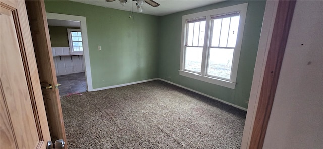 carpeted empty room with ceiling fan and a wealth of natural light