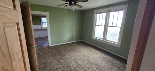 unfurnished room with ceiling fan and dark carpet