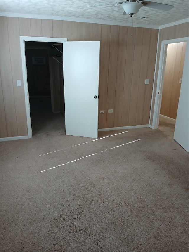 spare room with carpet floors, wooden walls, a textured ceiling, and ceiling fan