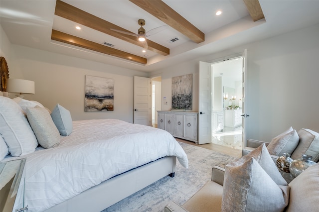 bedroom featuring light wood-type flooring, beamed ceiling, ceiling fan, a tray ceiling, and ensuite bathroom