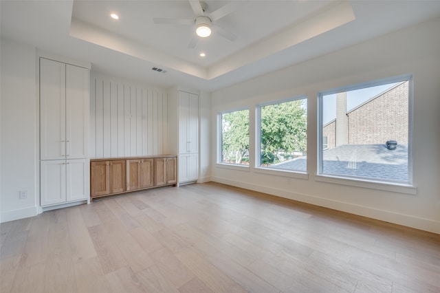 interior space featuring ceiling fan, a raised ceiling, and light hardwood / wood-style floors