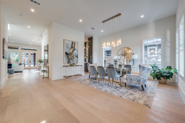 dining area with light wood-type flooring, french doors, and a chandelier