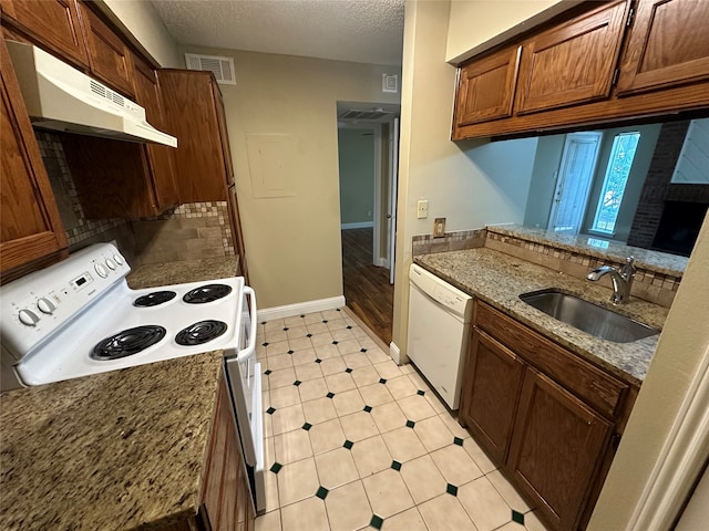 kitchen featuring white appliances, sink, decorative backsplash, light stone countertops, and a textured ceiling