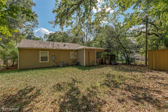 back of property with a yard and central AC