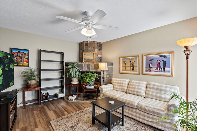 living room featuring a fireplace, ceiling fan, dark hardwood / wood-style floors, and a textured ceiling