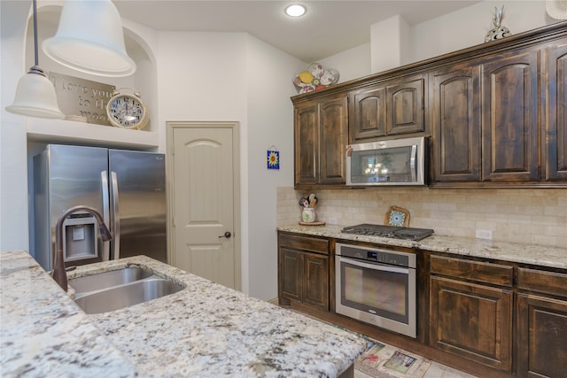 kitchen featuring decorative backsplash, hanging light fixtures, sink, dark brown cabinets, and appliances with stainless steel finishes