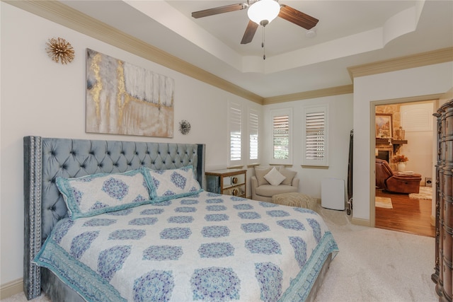 bedroom featuring ornamental molding, a tray ceiling, light colored carpet, and ceiling fan