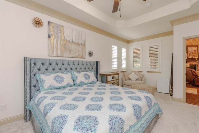 carpeted bedroom with ceiling fan, a raised ceiling, and crown molding