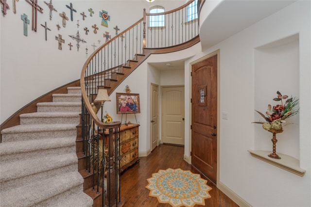 foyer entrance featuring a towering ceiling and dark hardwood / wood-style floors