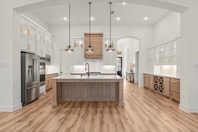 kitchen featuring a large island, decorative light fixtures, white cabinetry, appliances with stainless steel finishes, and light hardwood / wood-style floors