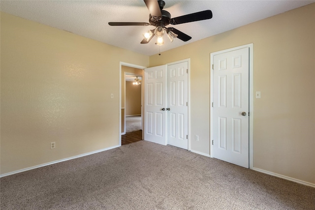 unfurnished bedroom featuring ceiling fan, multiple closets, carpet, and a textured ceiling