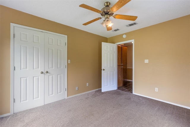 unfurnished bedroom featuring ceiling fan, a closet, and carpet flooring