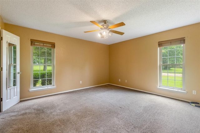 carpeted spare room featuring ceiling fan, a wealth of natural light, and a textured ceiling