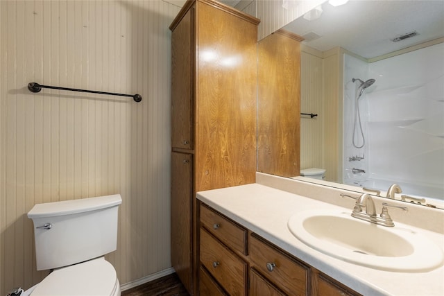 full bathroom with tub / shower combination, vanity, wood walls, and toilet