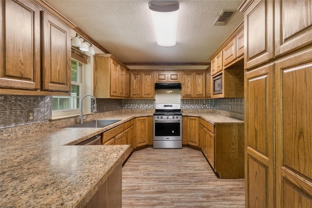 kitchen with ornamental molding, sink, a textured ceiling, appliances with stainless steel finishes, and light hardwood / wood-style floors