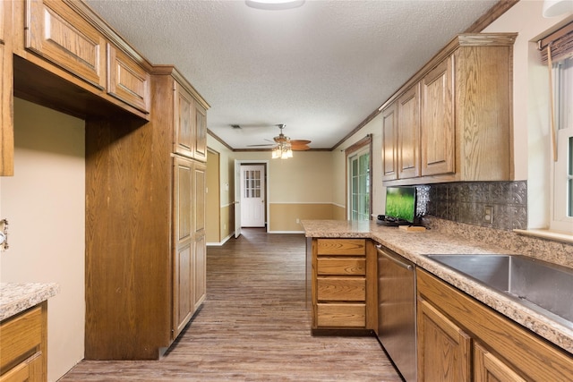 kitchen featuring light wood-type flooring, dishwasher, kitchen peninsula, ornamental molding, and a textured ceiling