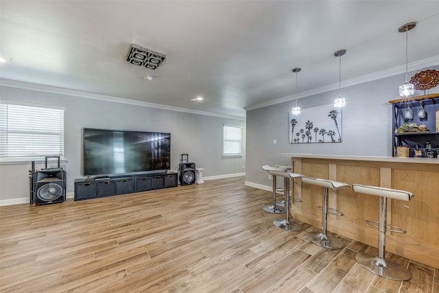 bar featuring light wood-type flooring, hanging light fixtures, ornamental molding, and plenty of natural light