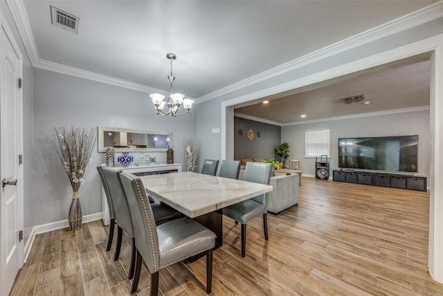 dining room with light wood-type flooring, crown molding, and an inviting chandelier