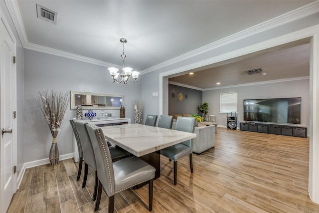 dining space with visible vents, ornamental molding, an inviting chandelier, light wood-style floors, and baseboards