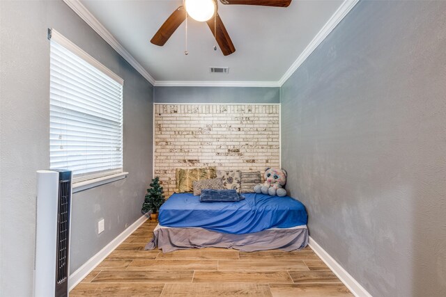 bedroom featuring ceiling fan, visible vents, wood finished floors, baseboards, and ornamental molding