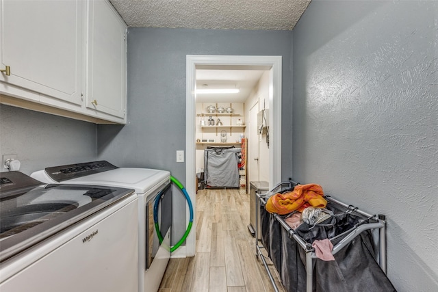 laundry area featuring a textured ceiling, independent washer and dryer, light wood-type flooring, cabinet space, and a textured wall